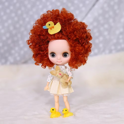 Middie Blythe Doll with red afro hair, cute dress, holding a toy, and wearing yellow duck slippers.