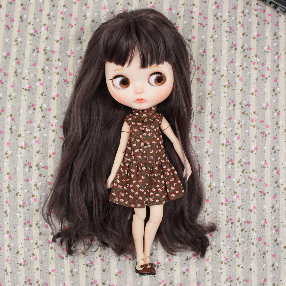 A Neo Blythe doll wearing a brown floral dress, showcasing long dark hair and an adorable expression on a patterned background.