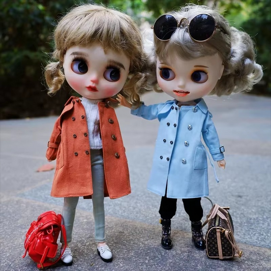 Two Neo Blythe dolls dressed in stylish trench coats, one orange and one blue, posing outdoors.