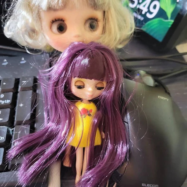 Mini Blythe dolls with purple and blonde hair on a desk, showcasing their unique designs and open/close eyes.